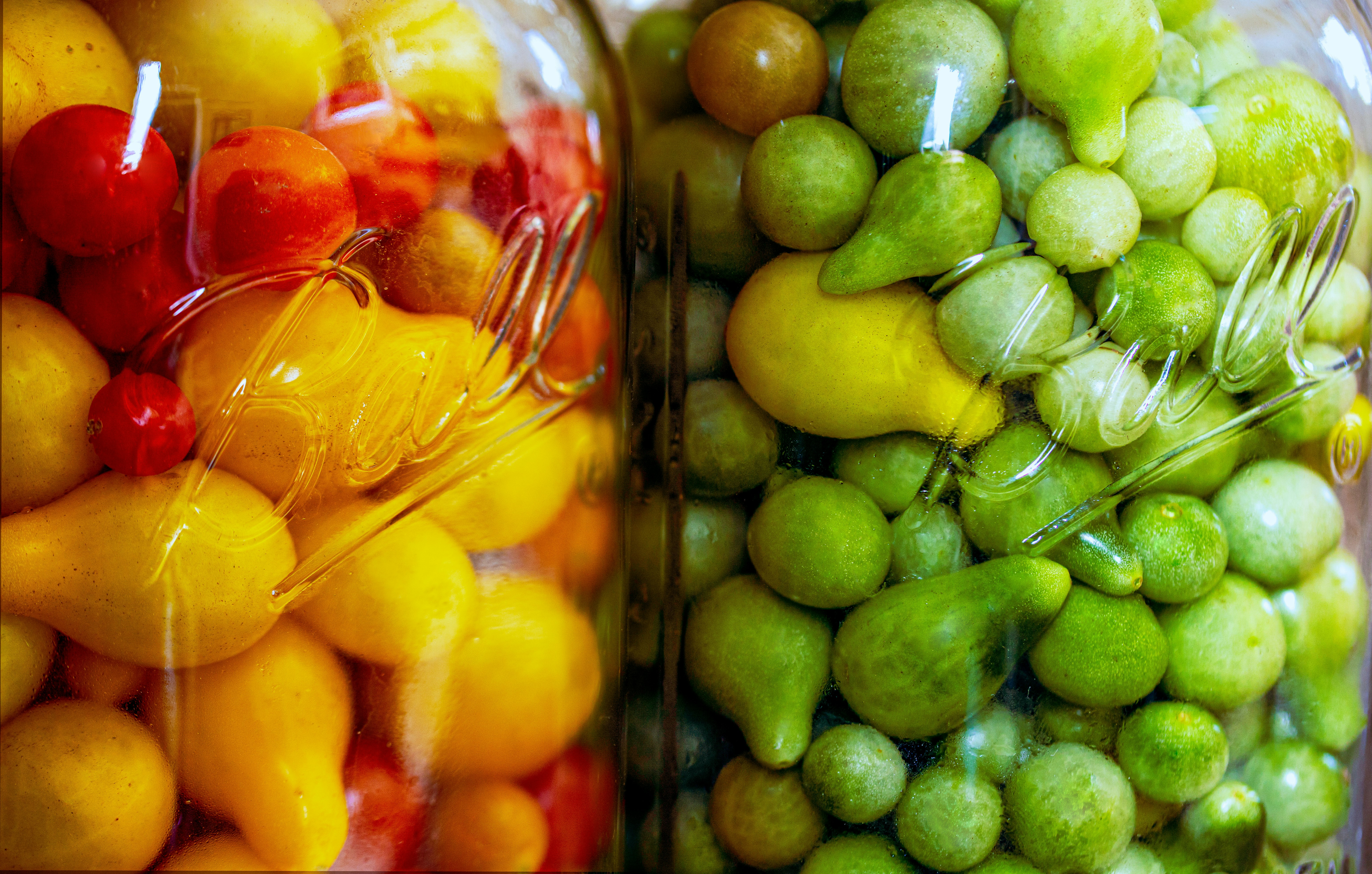 green and yellow fruits in clear glass jar